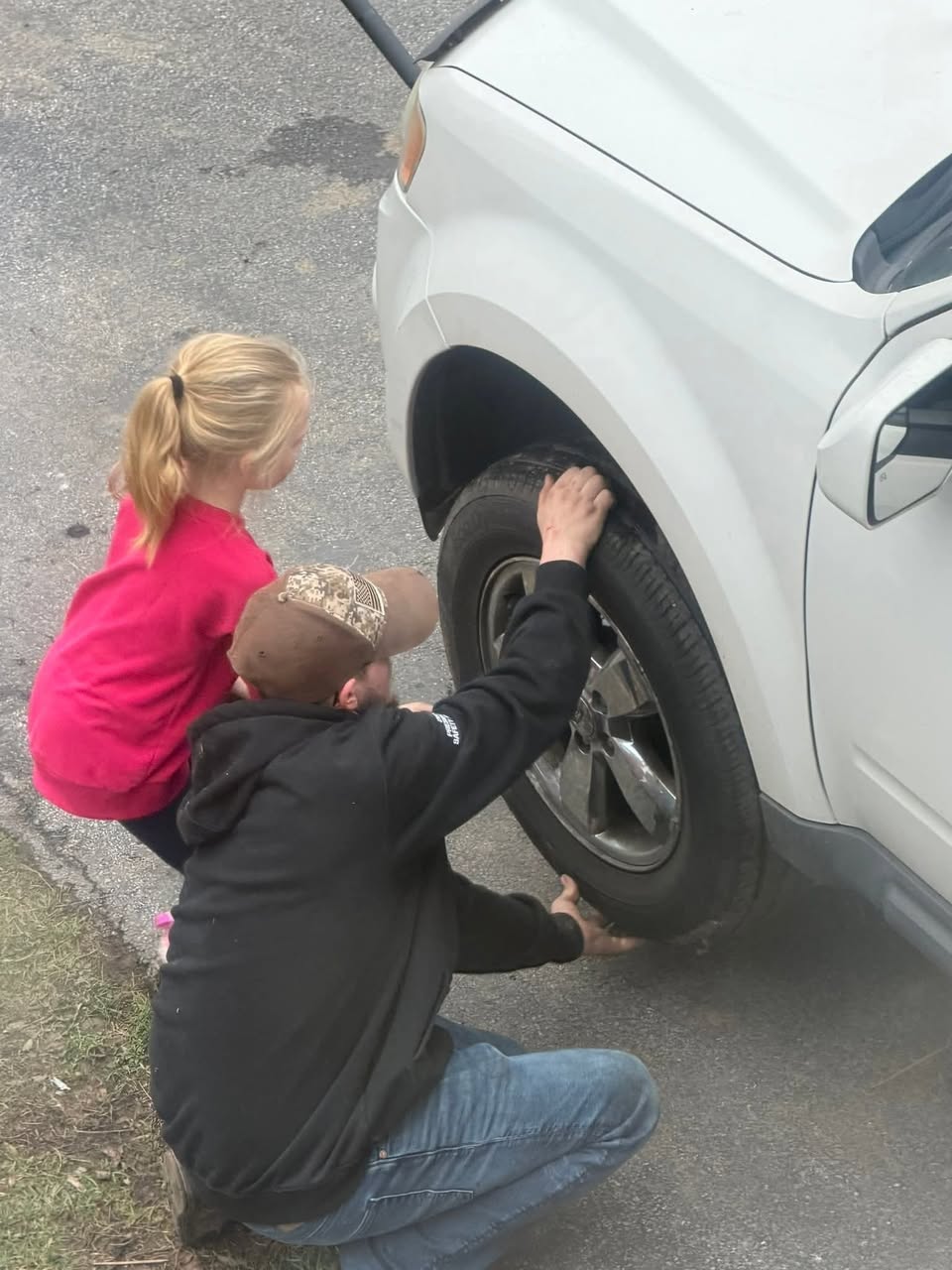 Sam showing a young girl how to inspect a tire