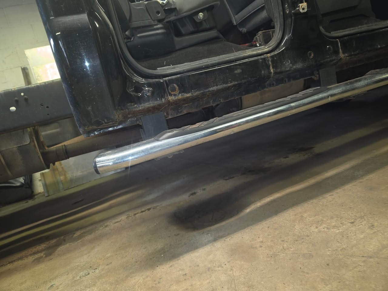Exposed lower rocker area on a black Ford Super Duty during inspection